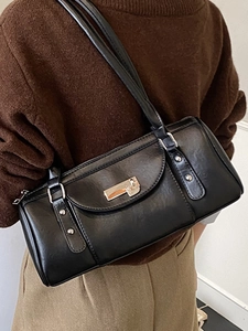 Minimalist black faux leather underarm baguette bag with silver buckle worn on shoulder
