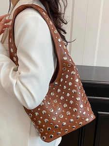 Brown leather underarm bucket bag with silver metal studs and bohemian style strap