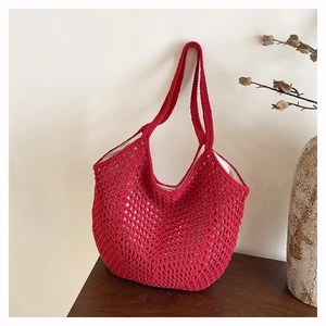 Detail of red hollow crochet tote bag with white lining on a wooden table setup