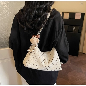 Detail of polka dot shoulder bag with plush teddy bear pendant in home setting