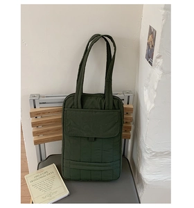 Close-up of olive green quilted tote bag with vertical stitching and front flap pocket