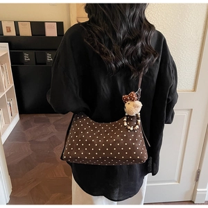 Detail of brown polka dot shoulder bag featuring a cute plush bear charm and beaded accent