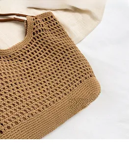 Close-up of woven straw tote bag featuring intricate mesh texture and leather handles