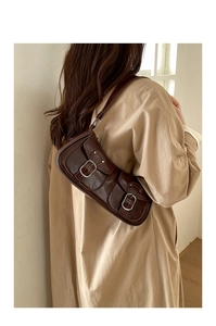 Dettaglio della borsa baguette vintage marrone scuro con pelle a pieghe e tasche con fibbia