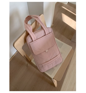 Detail of pink quilted tote bag with front pocket shown on a wooden chair