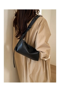Minimalist black leather shoulder bag styled on model with a clean interior background