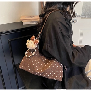 Detail of brown polka dot shoulder bag with cute plush bear charm and beaded strap