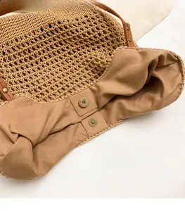 Detailed view of the magnetic metal buckle and fabric lining inside the straw tote bag