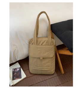 Detailed view of the vertical quilted texture and front flap pocket on a khaki tote bag