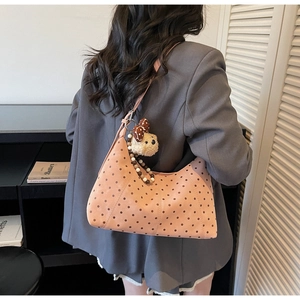 Detail of pink polka dot shoulder bag featuring beaded handle and cute bear charm pendant