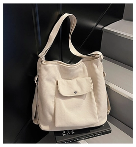 Detail of beige corduroy tote bag showing ribbed texture and front pocket with snap button