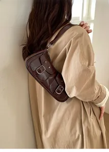 Dettaglio borsa a spalla marrone scuro in pelle cerata con doppie tasche a fibbia e texture