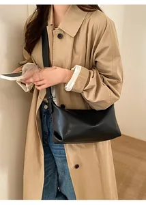 Minimalist black baguette shoulder bag shown as part of an elegant beige trench coat outfit