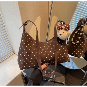 Detail of brown polka dot shoulder bag featuring a cute plush bear charm and beads