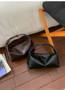 Detail view of black and dark brown minimalist crescent bags on wooden floor texture