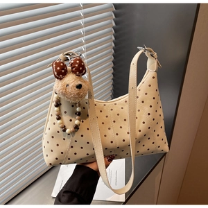 Detailed macro view of cream polka dot shoulder bag with cute plush bear charm accessory