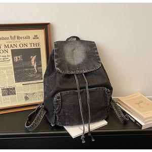 Detail of vintage washed denim backpack with drawstring closure and front zipper pocket