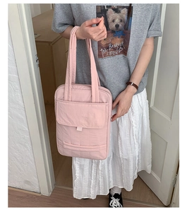 Detail of light pink quilted tote bag showing horizontal stitching and front flap pocket