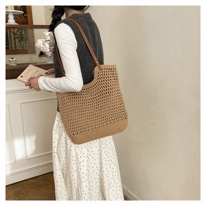 Close-up of woven tote bag with hollow grid pattern and brown leather shoulder straps