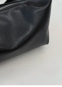 Close-up of black lychee texture leather shoulder bag with durable silver metal zipper