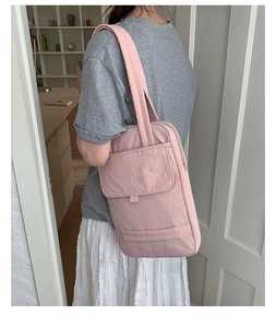 Pink waterproof nylon tote bag with side pocket shown on shoulder in a bright interior