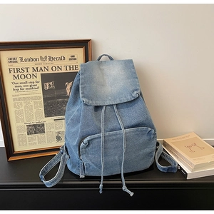 Detail of vintage washed denim backpack featuring drawstring closure and front zip pocket
