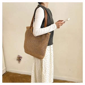 Detail of hand-woven straw tote bag with brown leather straps for seaside vacations