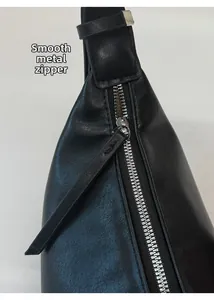 Detail of silver hardware zipper on black textured leather baguette bag with puller