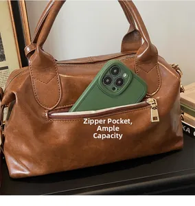 Detail of side zipper pocket on brown leather tote showing storage capacity for phone