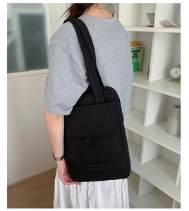 Detail of black commuter tote bag featuring functional front pocket with flap closure