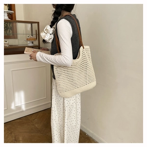 Straw tote bag detail featuring hollow woven mesh and slim brown leather shoulder straps