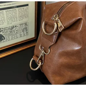 Close-up of premium gold-tone metal hardware and brown leather texture on handbag
