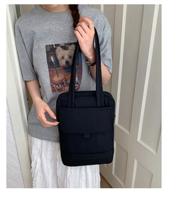 Close-up of black commuter tote bag with functional front flap pocket and sturdy shoulder straps