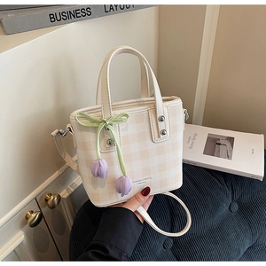 Détail du sac seau à carreaux beige avec breloque tulipe violette sur velours bleu