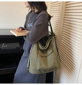 Side view of green corduroy tote bag with front pocket showing slouchy texture and large capacity