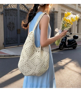 Close-up of cream woven tote bag with hollow floral crochet patterns worn outdoors