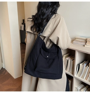 Detail of black corduroy shoulder bag with metal buckle pocket worn over a trench coat
