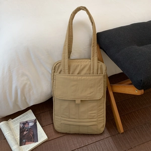 Detailed view of the khaki quilted tote bag featuring a magnetic flap front pocket on the floor
