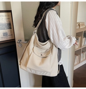 Close-up of beige corduroy tote bag showing ribbed texture and front pocket with metal buckle