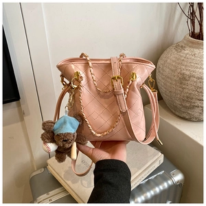 Détail du sac seau rose matelassé brillant avec bandoulière chaîne dorée et ours peluche