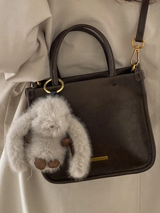 Classic dark brown crossbody bag with leather texture and cute grey plush bunny charm