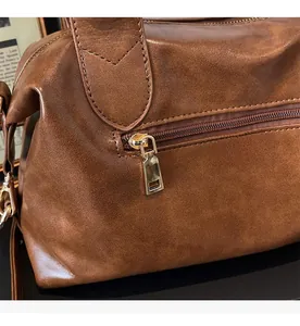Detail of smooth gold zipper and pebble leather texture on a vintage brown tote bag