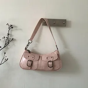 Dettaglio di borsa a spalla in pelle rosa vintage con tasche e fibbie in bronzo