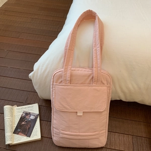 Detail of pink quilted tote bag with front flap pocket and soft stitched texture