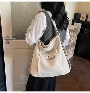 Detail of a cream corduroy tote bag featuring a front pocket and soft ribbed texture