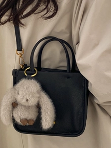 Classic black leather crossbody bag for women featuring a grey plush rabbit charm