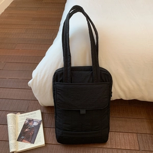 Close-up of a large black quilted tote bag with multi-compartments for office commute