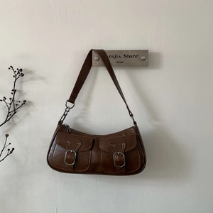 Dettaglio di una borsa vintage in pelle marrone scuro con tasche a fibbia e texture vissuta