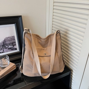 Detailed close-up of khaki corduroy tote bag texture with metal snap button pocket