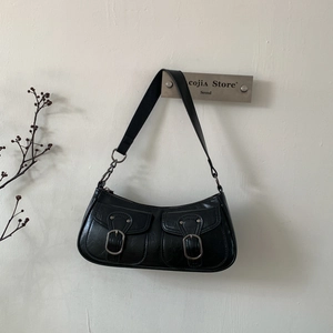 Dettaglio della borsa sottobraccio in ecopelle nera con tasche decorative e fibbie metalliche
